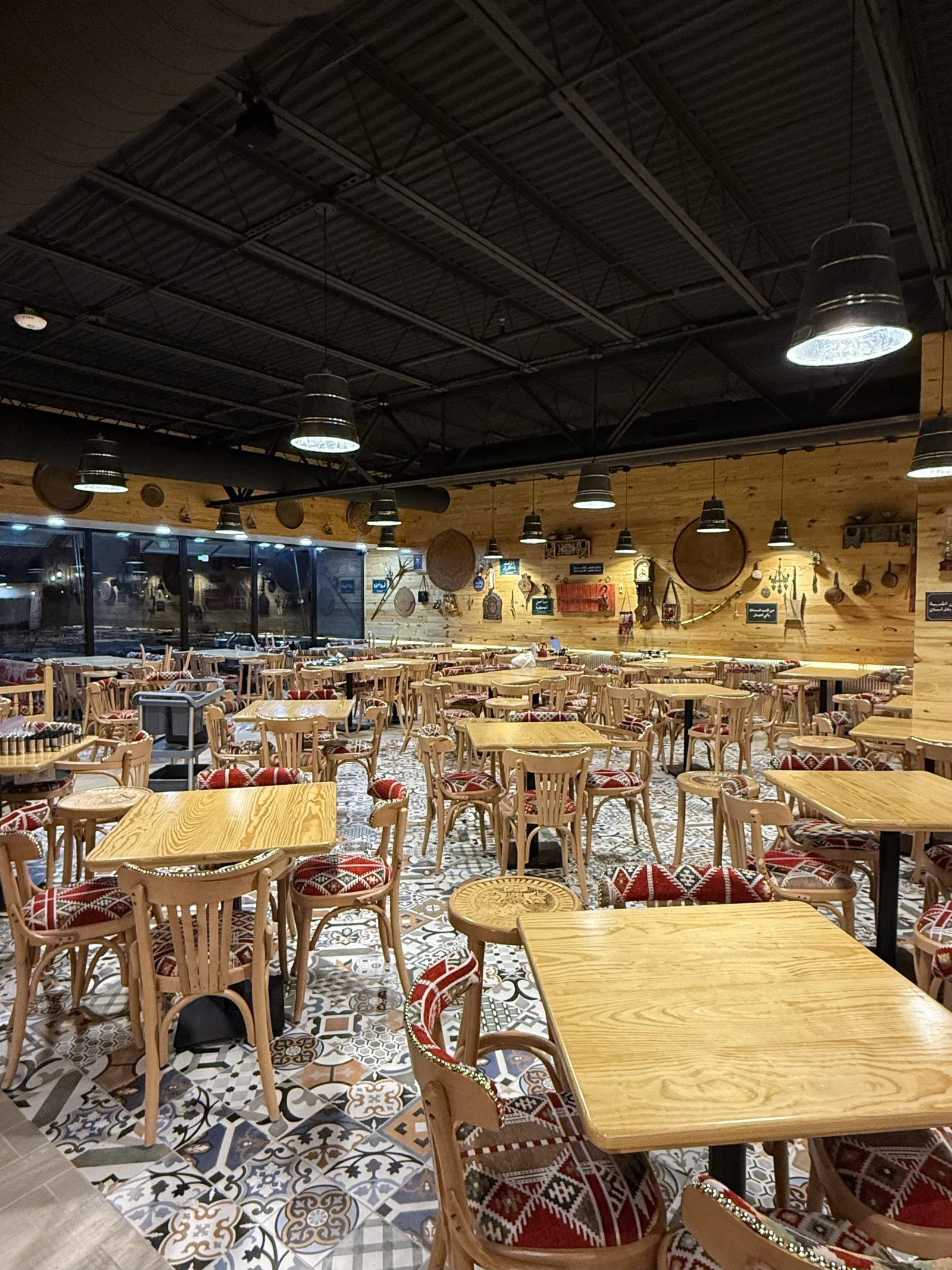 The empty dining room with wood tables and tatreez cushions at Khashoka in Richardson